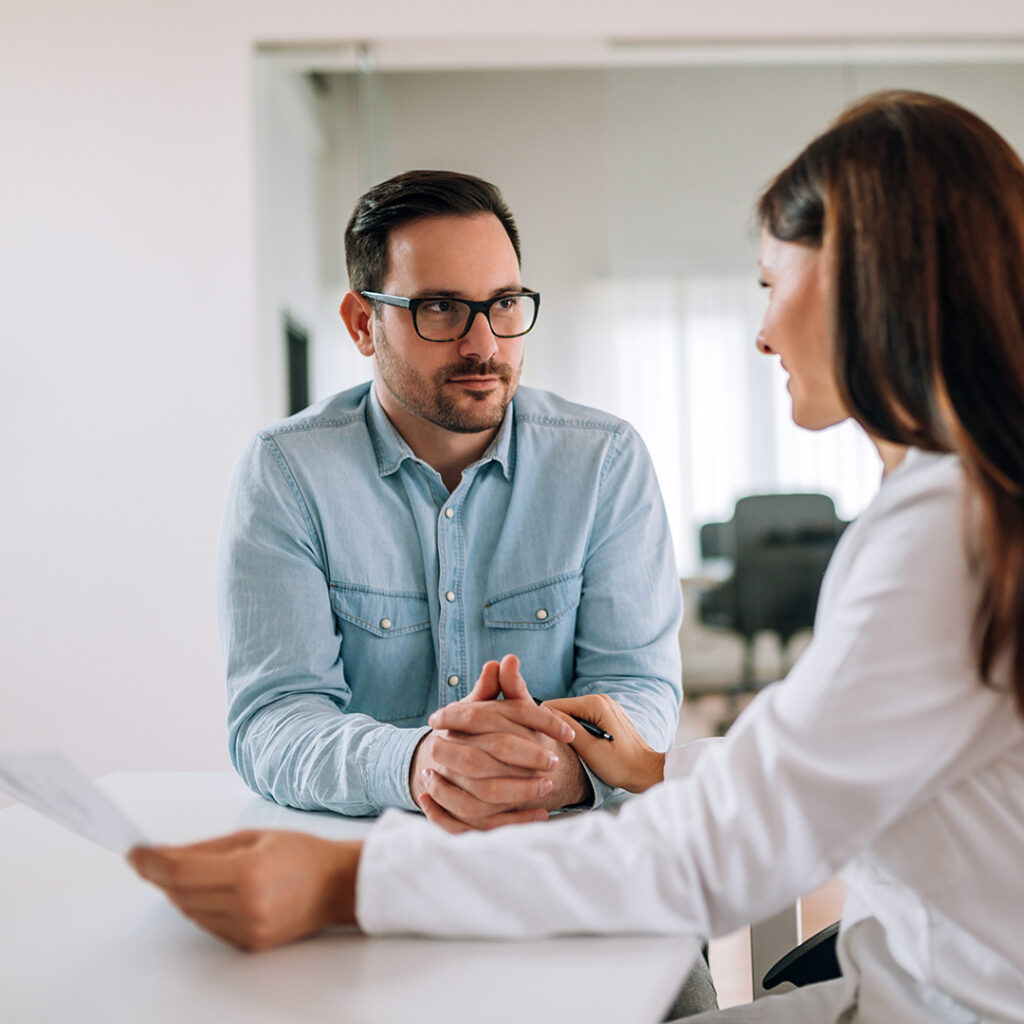 Dr. Mariana Jaramillo in consultation with a patient, holding a paper and sharing positive news about the benefits of autoimmune care therapy, representing the successful outcomes of this treatment.