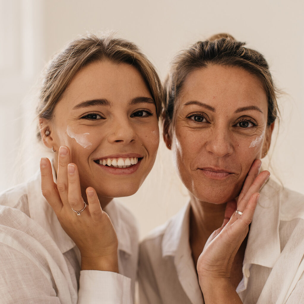 Mother and daughter each touching their own faces, illustrating the benefits and rejuvenating effects of Anti-Aging Stem Cell Treatment on their skin